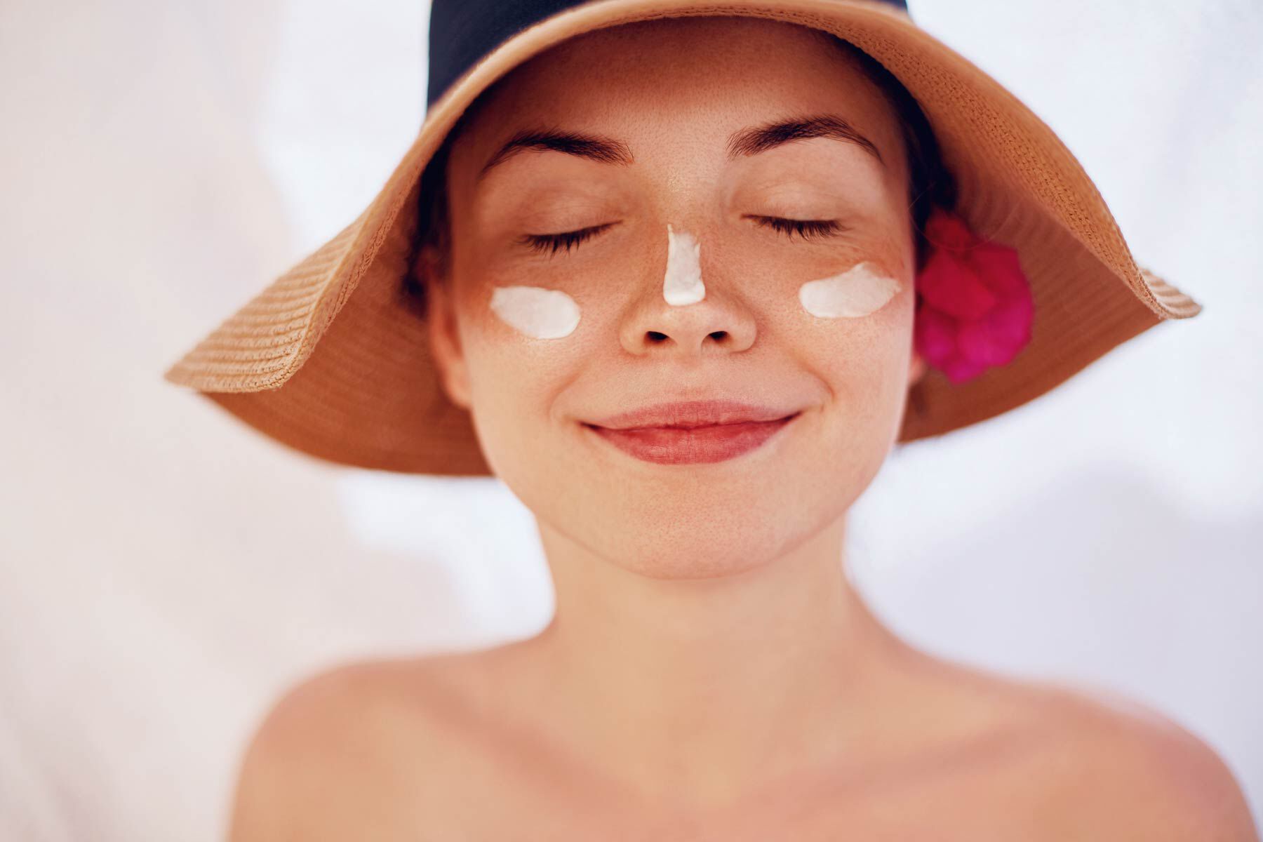 Woman wearing sunscreen and sun hat with eyes closed